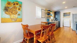 A dining area with a wooden table and chairs, a kitchen with modern appliances, and a painting on the wall. - Modern cozy house with full kitchen, dining & living area, TV, close to downtown (Austin)