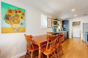 Ein Essbereich mit Holztisch und -stühlen, eine Küche mit modernen Geräten und ein Bild an der Wand.
