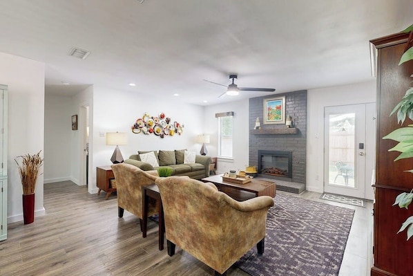 A living room with a fireplace, a ceiling fan, and a coffee table. - Cozy home with enclosed backyard and fire pit - Dog-friendly (Austin)