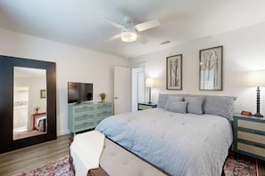 A bedroom with a bed, a ceiling fan, a TV, a dresser, and framed artwork on the wall. - Cozy home with enclosed backyard and fire pit - Dog-friendly (Austin)