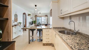A kitchen with a granite countertop, stainless steel sink, and bar stools. - Charming 2-bedroom Apartment With Ocean Views in Adeje (Adeje)