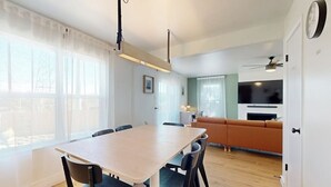 Un salon moderne comprenant une table à manger, des chaises, un canapé et un téléviseur.