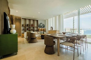 Ein modernes Interieur mit Essbereich, einer Sofagarnitur, einem grünen Schrank und einem großen Fenster mit Aussicht.