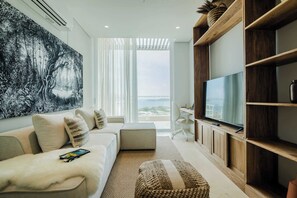 Ein modernes Wohnzimmer mit großem Flachbildfernseher, einer Couch, einem Couchtisch und einem großen abstrakten Gemälde.