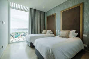 Ein Hotelzimmer mit zwei Betten, einem großen Fenster und Blick ins Freie.