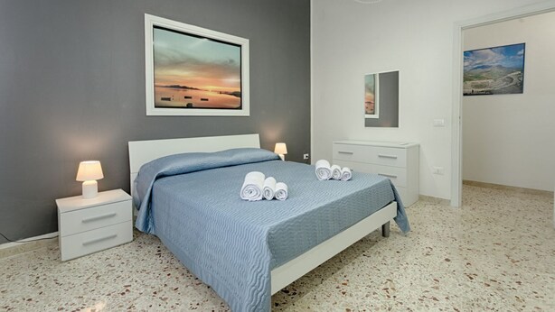 Een slaapkamer met een bed, nachtkastjes, een spiegel en kunstwerken aan de muur.