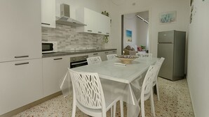 Een moderne keuken met witte kastjes, een roestvrijstalen koelkast en een eettafel met stoelen.