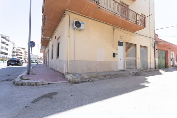 Straßenansicht, ein Gebäude mit Balkon, einem Verbotsschild und heruntergelassenen Rollläden im Erdgeschoss.