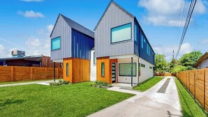 Ett modernt hus i två våningar med ett garage, en välskött gräsmatta och en klar himmel.