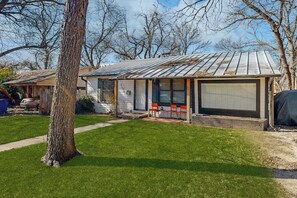 Ein eingeschossiges Haus mit einer Metallbedeckung, einer Veranda mit zwei Stühlen und einer Garage mit geschlossener Tür.