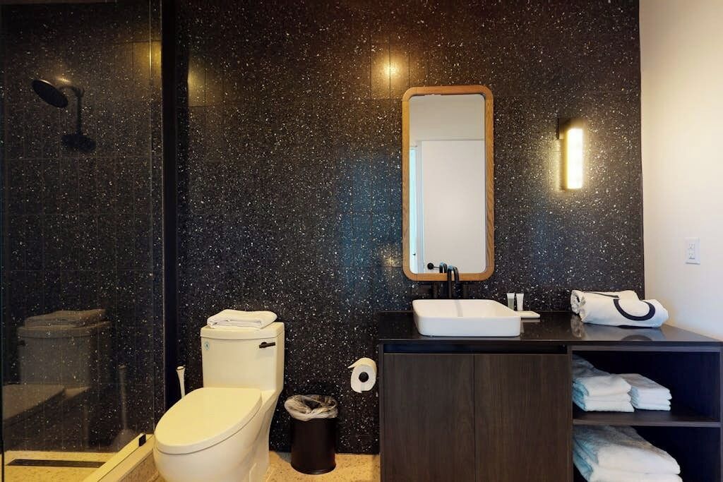 Et badeværelse med toilet, håndvask, spejl og håndklædestang.