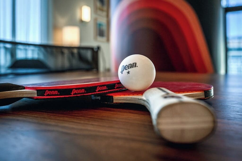 A table with a table tennis paddle, a ball, and a paddle.