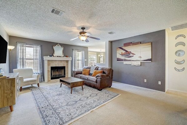 A living room with a fireplace, a sofa, a coffee table, and a ceiling fan.