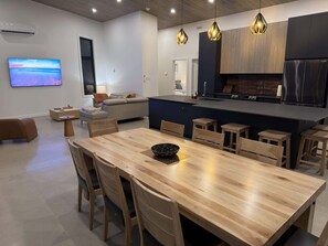 Una cocina moderna con una isla central, mesa de comedor de madera y taburetes de bar.