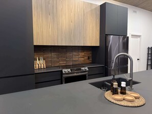 Una cocina moderna con gabinetes negros, un refrigerador de acero inoxidable, una estufa a gas y un lavamanos con grifo.