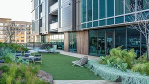 En modern byggnad med en innergård, utomhusmöbler och ett stort utbud av växter.