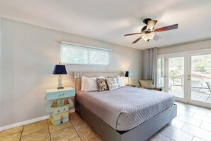 A bedroom with a bed, nightstands, a ceiling fan, a window with blinds, and a view through a glass door. - Chic home on Lake Austin with dock, lovely deck, vibrant interior & views (Austin)