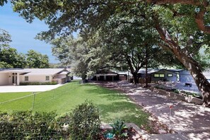 A residential area with houses, a well-maintained lawn, and trees. - Chic home on Lake Austin with dock, lovely deck, vibrant interior & views (Austin)