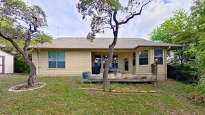 Ein eingeschossiges Haus mit Veranda, kleinem Vorgarten und Baum.