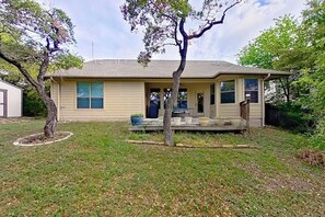 A single-story house with a front porch, a small yard, and a tree in front. - Scenic retreat with fenced yard, patio, central AC, & washer/dryer (Austin)