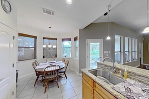A kitchen with a dining table, chairs, a sink, and a window. - Scenic retreat with fenced yard, patio, central AC, & washer/dryer (Austin)