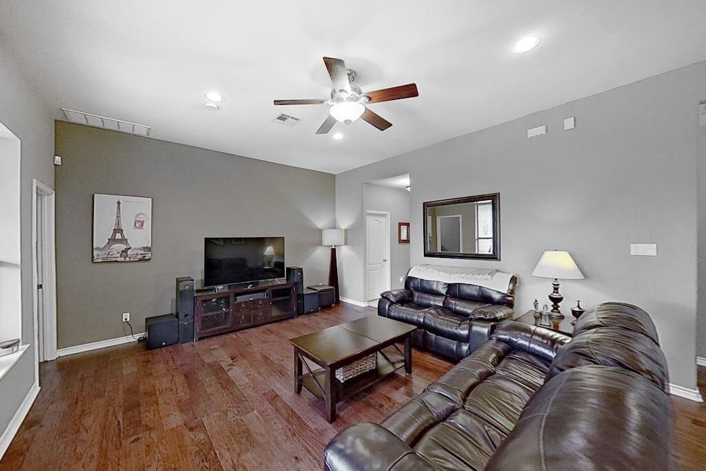 A living room with a ceiling fan, a television, a leather sofa, and a coffee table.