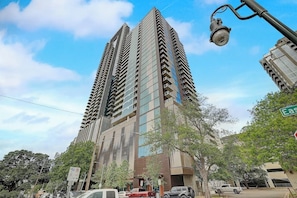 A tall, modern building with multiple floors, large windows, and a street lamp. - Historic Rainey St. condo with skyline views - rooftop pool & gym (Austin)
