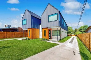 Ein modernes, zweigeschossiges Haus mit Garage, gepflegtem Rasen und blauem Himmel.