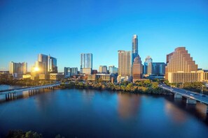 A city skyline with modern high-rise buildings, a river, and a bridge.