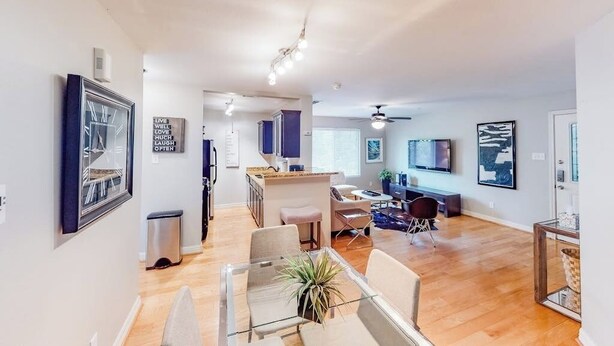 A modern living room with a dining area, a kitchen, and a TV mounted on the wall. - Lovely Austin condo close to downtown with streaming, W/D, central AC, & WiFi (Austin)