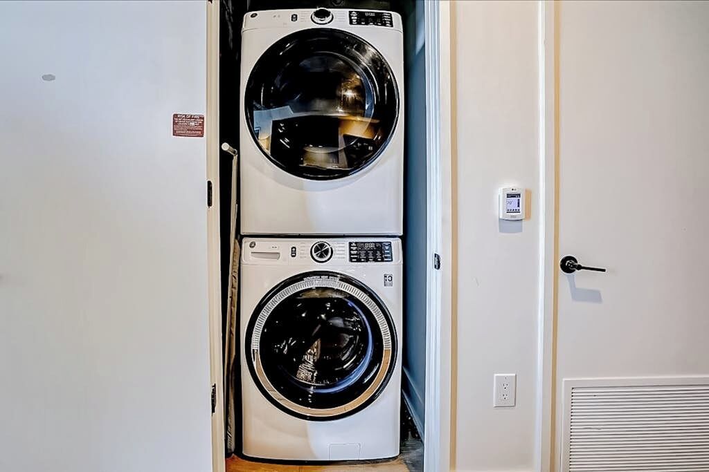 A laundry room with two stacked front-loading washing machines and a door with a lock.