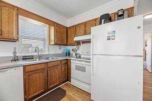Eine Küche mit Holzschränken, einem weißen Kühlschrank, einem Herd und einem Spülbecken.