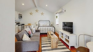 Un espace de vie compact comprenant un coin cuisine, un lit avec une tête de lit, un téléviseur et un canapé.