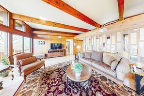 Ein geräumiges Wohnzimmer mit einer großen Couch, einem Couchtisch und einem Fernseher im Hintergrund.