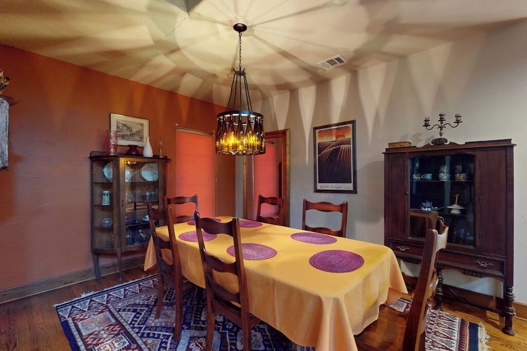 Een eetzaal met een tafel gedekt voor vier personen, een kroonluchter en een kast met glazen deuren.
