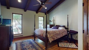 Une chambre à coucher avec un lit à baldaquin, un ventilateur de plafond et une grande fenêtre.