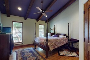 A bedroom with a four-poster bed, a ceiling fan, and a large window. - Charming home with balcony, firepit, & 2 living rooms - near dining & music (Austin)