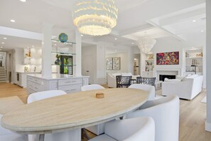 Ein modernes Interieur mit Essbereich, weißer Möbel und dekorativer Beleuchtung.