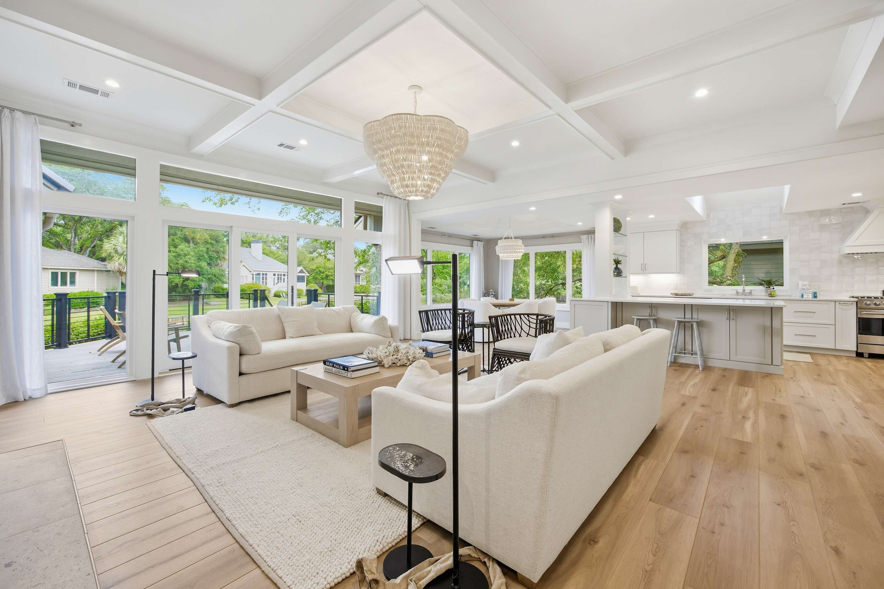 A spacious living area with a large sofa, a coffee table, and a floor lamp. There is a kitchen area with a countertop and cabinets.