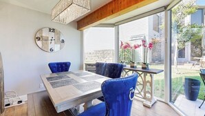 A dining area with a table, chairs, a clock, and a view of the outside. - Stylish Hideaway w/ Chic Kitchen & Private Patio - Located at World of Tennis (Lakeway)