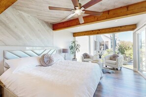 Ein Schlafzimmer mit einem großen Bett, einem Deckenventilator und Blick ins Freie.