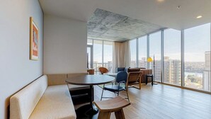 Un intérieur moderne avec une table ronde, des sièges et de grandes fenêtres offrant une vue sur la ville.