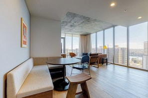 A modern interior with a round table, seating, and large windows offering a city view. - 13th floor corner condo, lake-view balcony, rooftop pool & gym, dog-friendly (Austin)