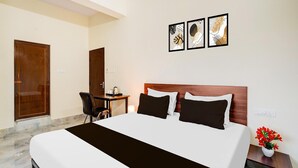 A hotel room with a bed, a desk, a chair, and a wall-mounted TV. - Deluxehennur Prakruthi Layout Bangalore (Bengaluru)