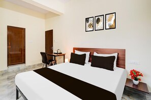 A hotel room with a bed, a desk, a chair, and a wall-mounted TV. - Deluxehennur Prakruthi Layout Bangalore (Bengaluru)