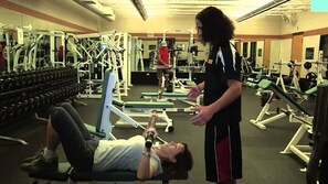 Une salle de sport équipée de divers appareils d’exercice, notamment des haltères et des machines de musculation.