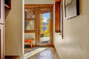 Eine Holztür, die zu einem Balkon mit Blick auf Bäume und Berge führt.