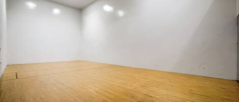 A room with a wooden floor, white walls, and recessed ceiling lights.