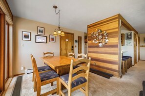 Ein Essbereich mit Holztisch und -stühlen, einer Deckenleuchte und einer Wand mit Holzpaneelen.