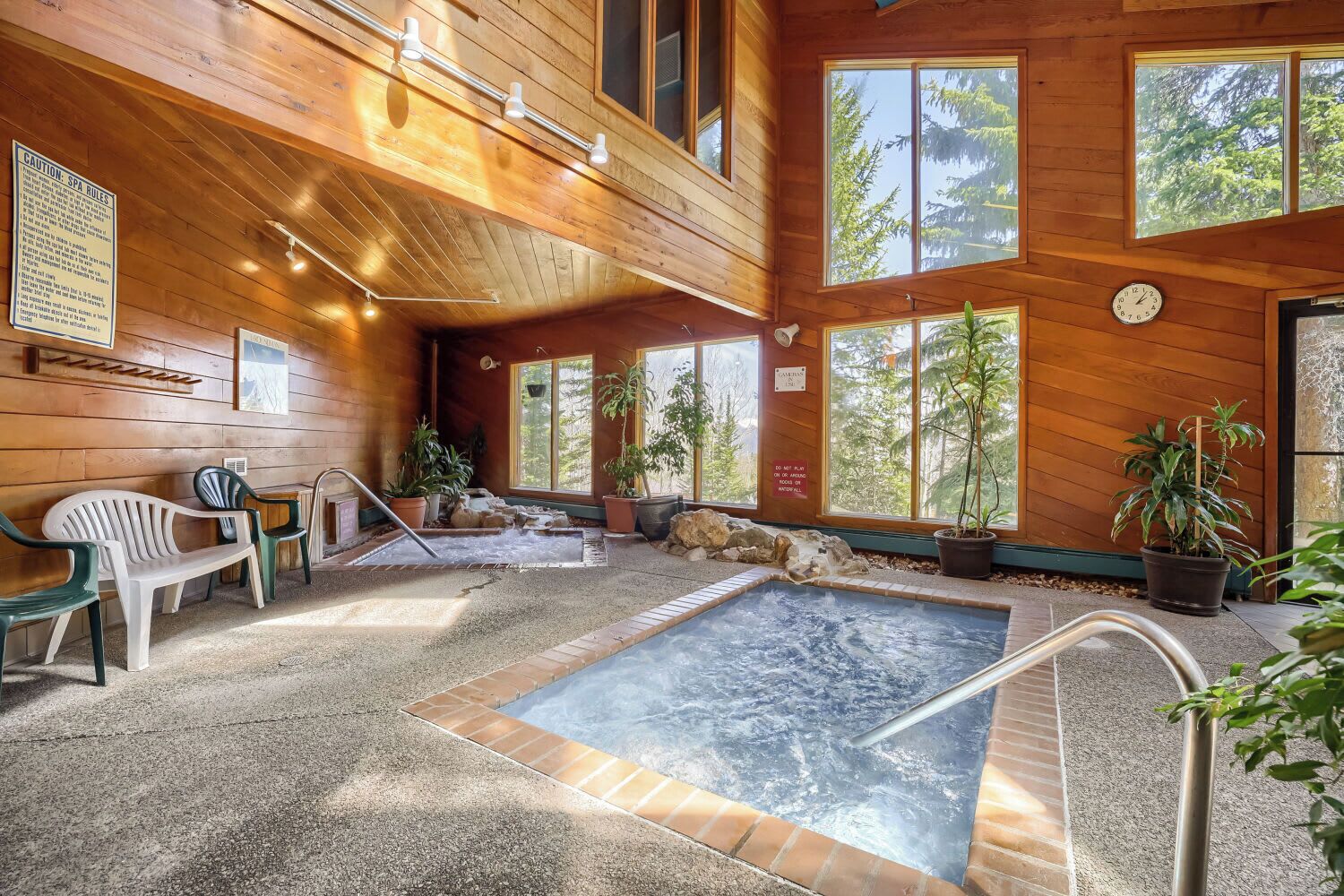 Zona de spa con un jacuzzi, asientos y plantas en macetas.